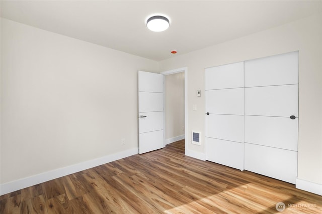 unfurnished bedroom with light wood-style flooring, baseboards, visible vents, and a closet