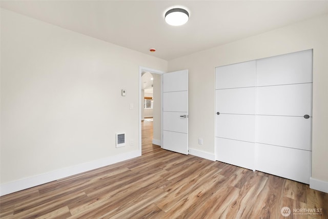 unfurnished bedroom featuring light wood-type flooring, baseboards, a closet, and visible vents