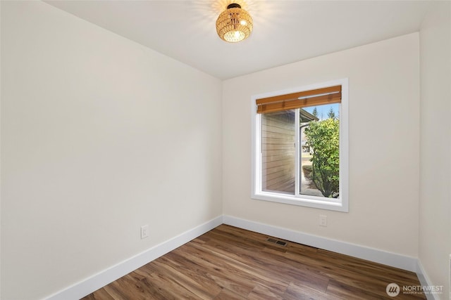 empty room with visible vents, baseboards, and wood finished floors