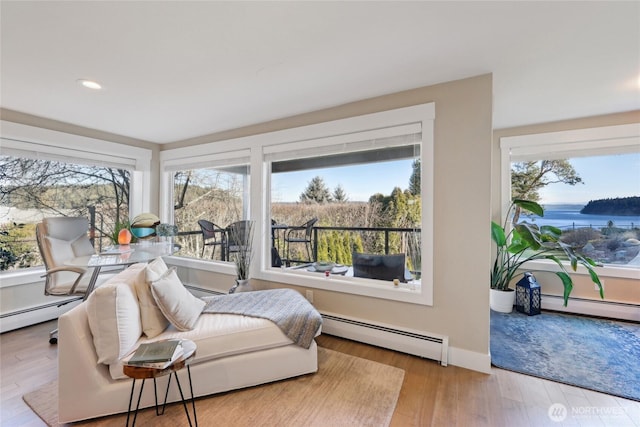 sitting room with baseboards, a baseboard heating unit, wood finished floors, and recessed lighting