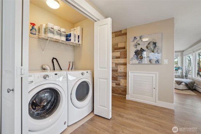 clothes washing area with washing machine and dryer, laundry area, baseboards, and light wood finished floors