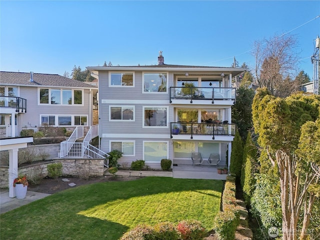 back of property with a yard, stairway, a chimney, and a balcony