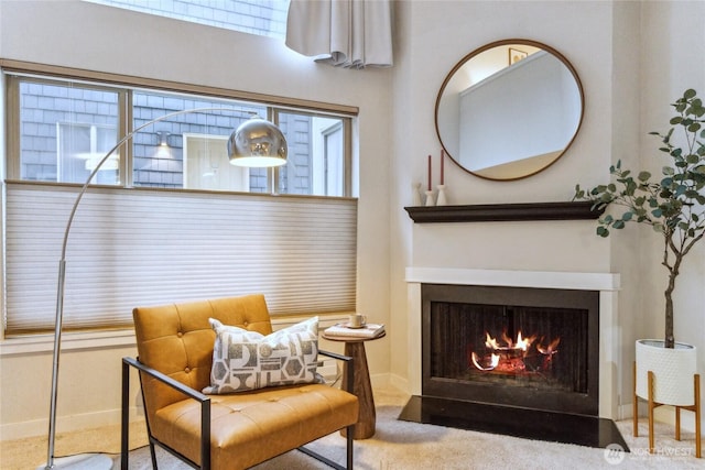 living area with carpet flooring, baseboards, and a fireplace with flush hearth