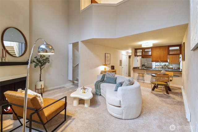 living room featuring light colored carpet, a high ceiling, and baseboards