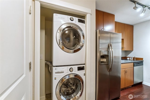 laundry area featuring dark wood-style floors and stacked washer / dryer