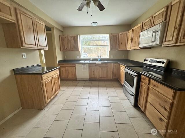 kitchen featuring a ceiling fan, dishwasher, dark countertops, stainless steel electric stove, and a sink