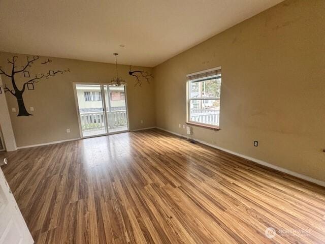 empty room featuring lofted ceiling, wood finished floors, and baseboards