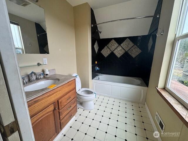 bathroom featuring shower / bathtub combination, toilet, vanity, visible vents, and a healthy amount of sunlight