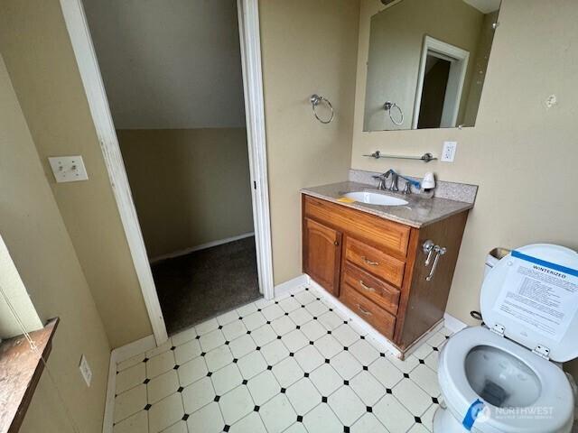 half bath with vaulted ceiling, vanity, and tile patterned floors