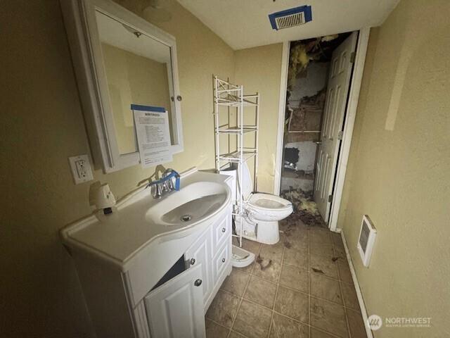 bathroom featuring toilet, vanity, and visible vents