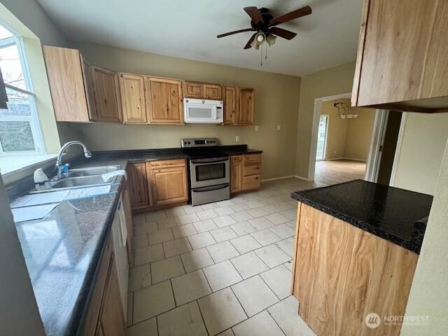 kitchen featuring dark countertops, white microwave, ceiling fan, stainless steel electric range, and a sink