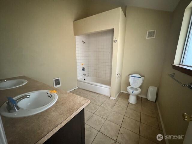 bathroom with double vanity, toilet,  shower combination, tile patterned flooring, and a sink