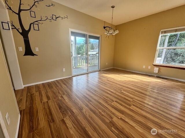 interior space with a chandelier, wood finished floors, and baseboards