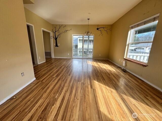 unfurnished dining area with baseboards, a chandelier, and wood finished floors