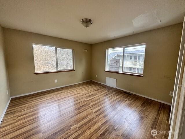 empty room featuring visible vents, baseboards, and wood finished floors