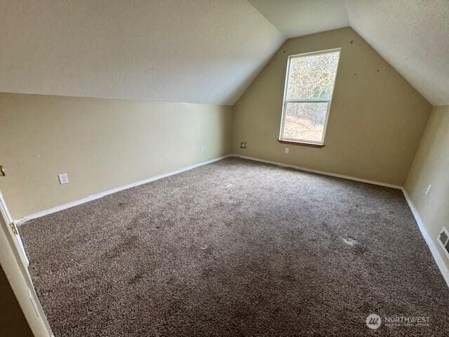 bonus room with a textured ceiling, carpet, lofted ceiling, and baseboards