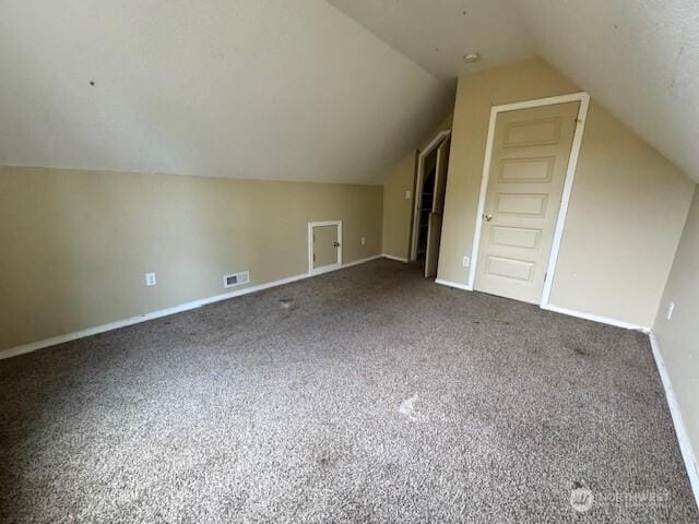 additional living space with carpet floors, baseboards, visible vents, and vaulted ceiling