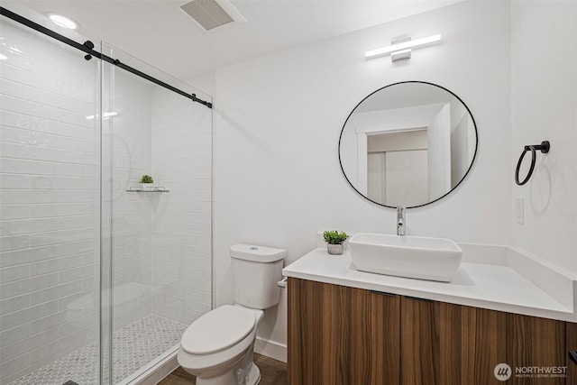 bathroom with visible vents, a shower stall, toilet, and vanity