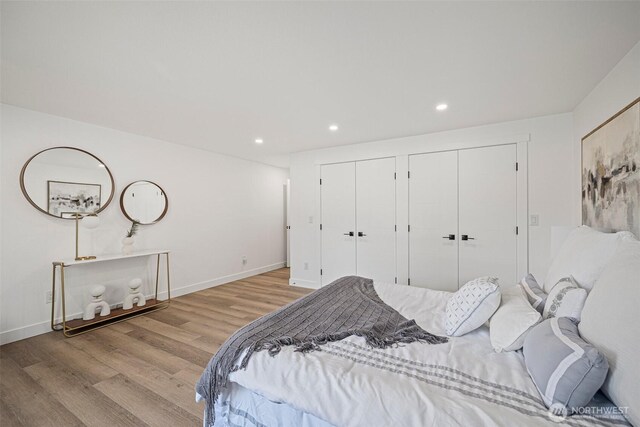 bedroom featuring recessed lighting, light wood-style flooring, baseboards, and two closets