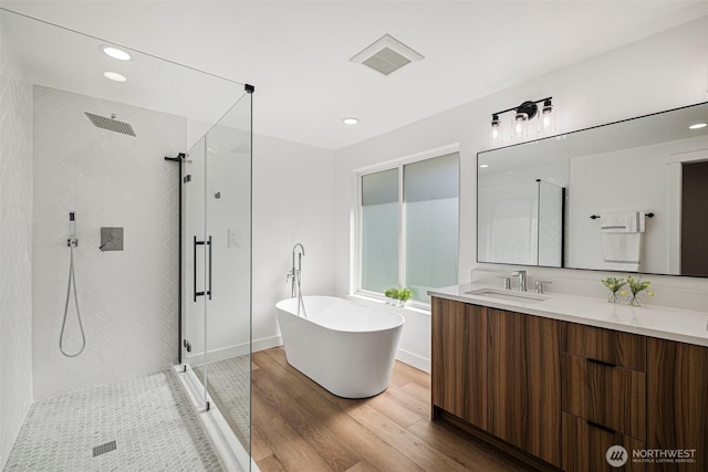 full bathroom featuring wood finished floors, vanity, visible vents, a freestanding bath, and a stall shower