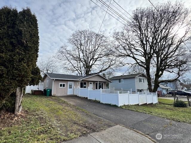 ranch-style home with a fenced front yard and aphalt driveway