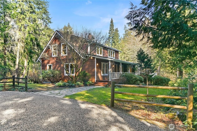 view of front of home with a front lawn, a chimney, fence, and a porch