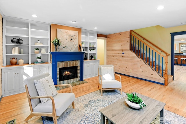 sitting room featuring visible vents, wood finished floors, stairs, a fireplace, and recessed lighting