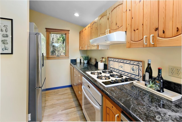 kitchen featuring lofted ceiling, light wood-style flooring, white appliances, under cabinet range hood, and baseboards