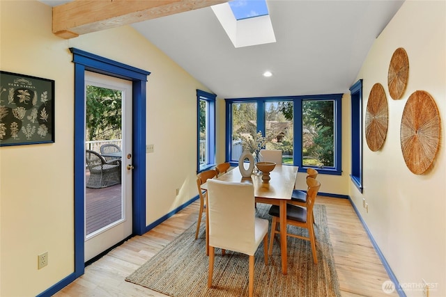 dining room with light wood-style floors, baseboards, and lofted ceiling with skylight