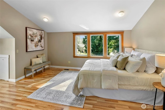 bedroom featuring vaulted ceiling, baseboards, and light wood-style floors