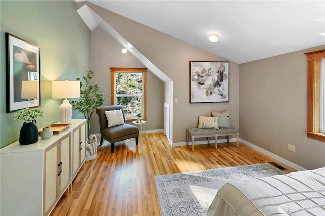 bedroom with light wood-type flooring, lofted ceiling, visible vents, and baseboards