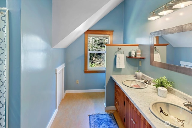 bathroom with vaulted ceiling, wood finished floors, a sink, and baseboards