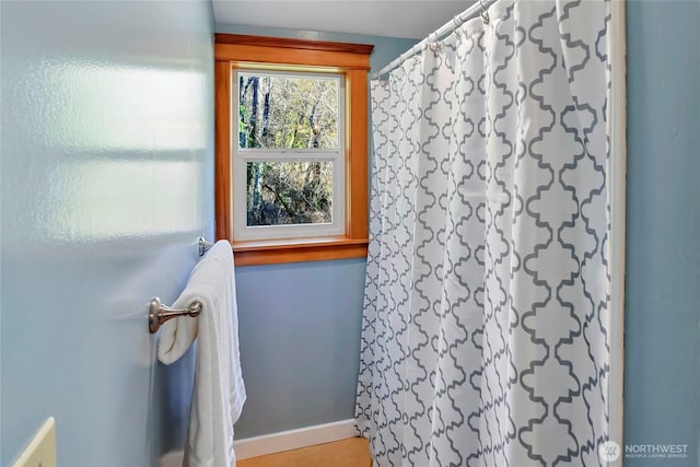 bathroom featuring curtained shower and baseboards