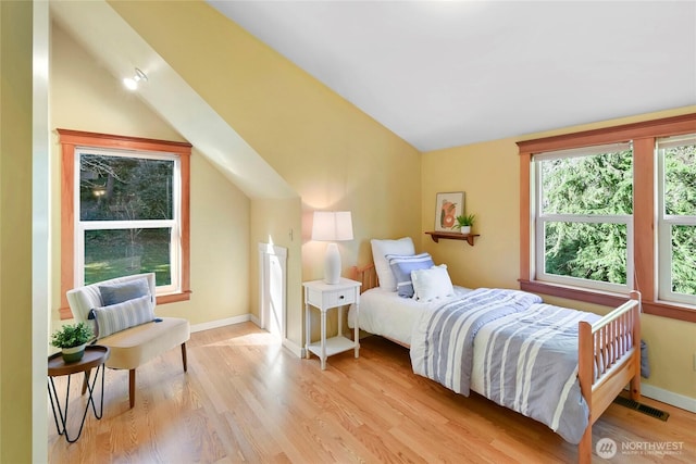 bedroom featuring light wood-type flooring, visible vents, vaulted ceiling, and baseboards