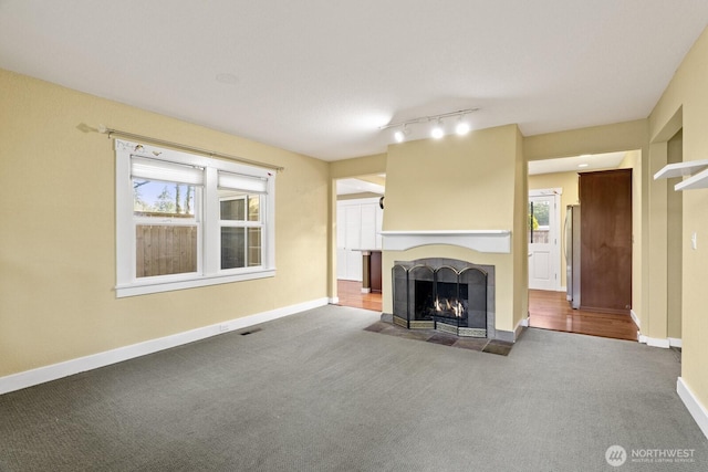 unfurnished living room with carpet flooring, a fireplace, visible vents, and baseboards