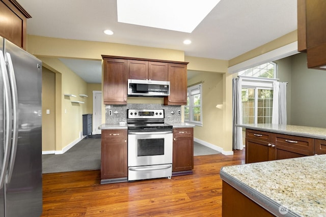 kitchen featuring stainless steel appliances, baseboards, dark wood-style flooring, and decorative backsplash