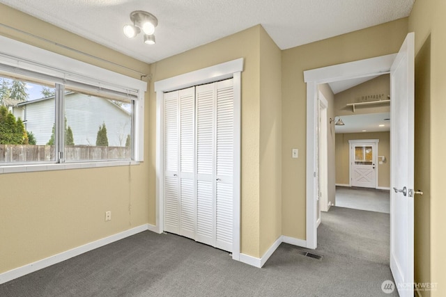 unfurnished bedroom with visible vents, baseboards, a closet, and dark carpet