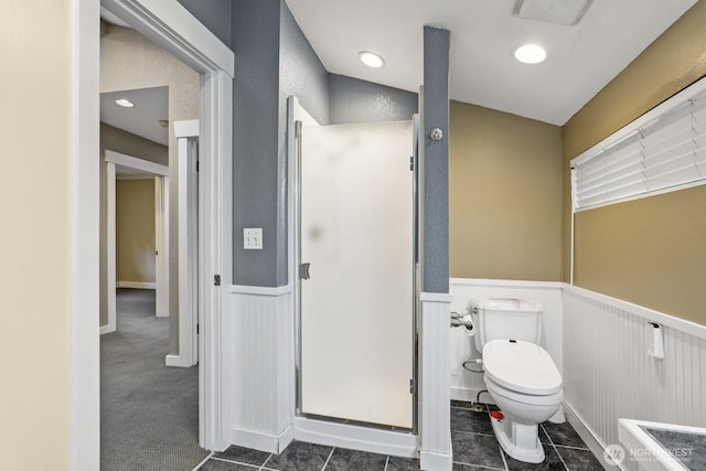 bathroom with recessed lighting, a stall shower, tile patterned flooring, wainscoting, and toilet