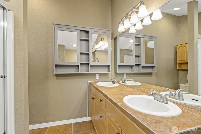 bathroom with double vanity, baseboards, and a sink