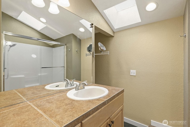 bathroom with vaulted ceiling, a shower stall, vanity, and a textured wall