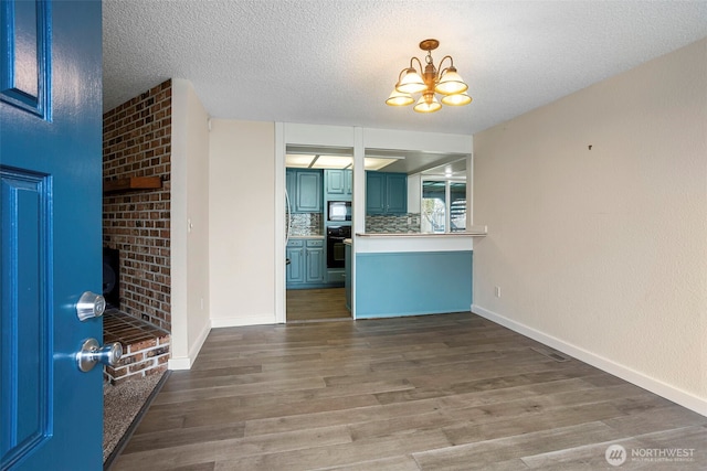 interior space with wood finished floors, oven, built in microwave, a textured ceiling, and blue cabinetry