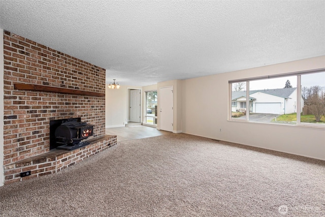 unfurnished living room featuring a wood stove, carpet, baseboards, and a textured ceiling