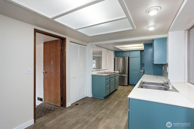 kitchen featuring wood finished floors, freestanding refrigerator, light countertops, blue cabinetry, and a sink