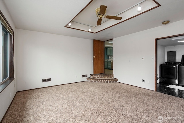 empty room featuring visible vents, ceiling fan, carpet flooring, separate washer and dryer, and track lighting