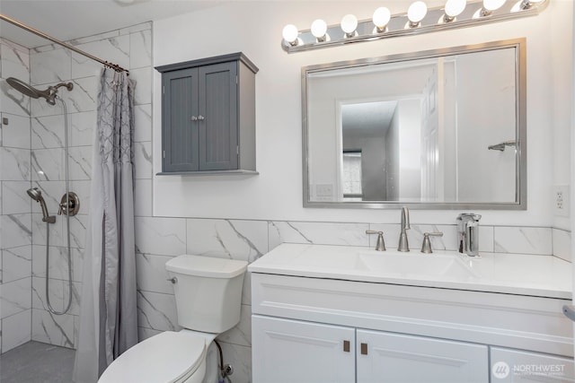 bathroom featuring toilet, a tile shower, vanity, and tile walls