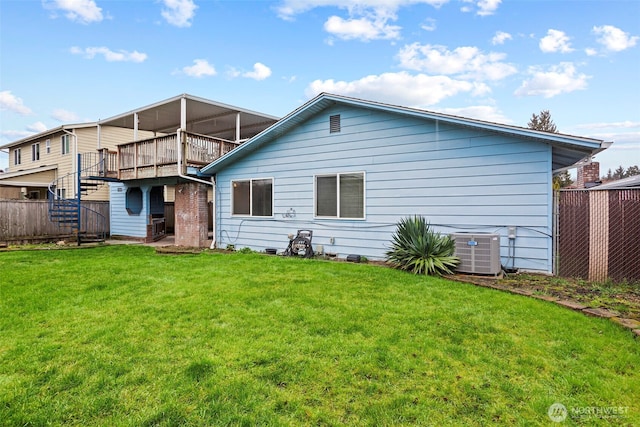 rear view of house featuring stairway, fence, cooling unit, and a yard