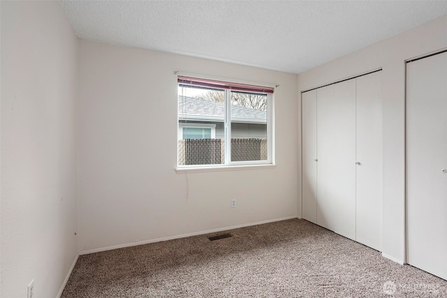 unfurnished bedroom with light carpet, a textured ceiling, visible vents, and baseboards