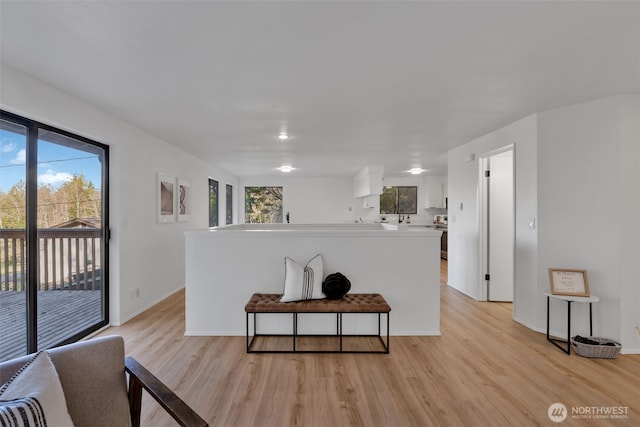 kitchen with baseboards, open floor plan, light countertops, white cabinets, and light wood finished floors