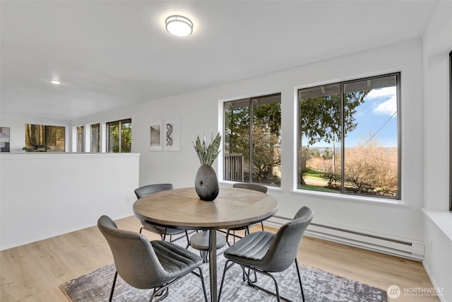 dining area featuring plenty of natural light, baseboard heating, and wood finished floors