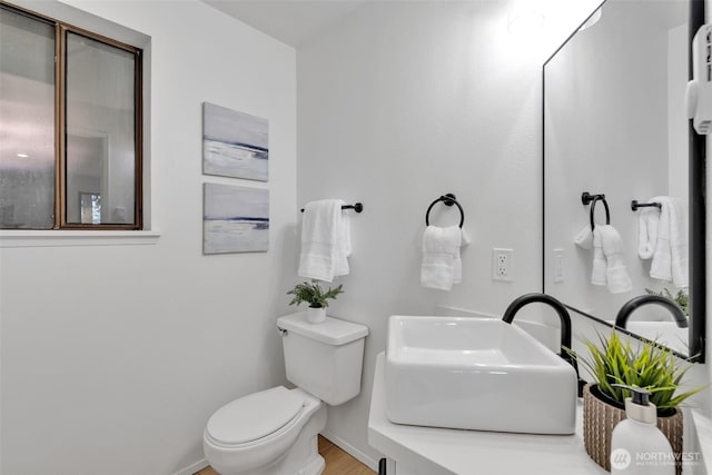 bathroom featuring toilet, baseboards, and a sink